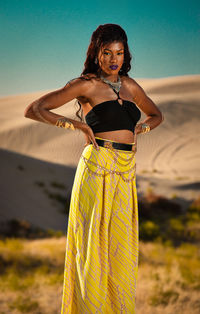 Portrait of young woman standing on land against the sky