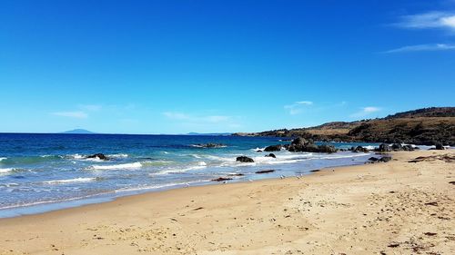 Scenic view of beach against blue sky