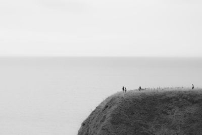 People walking on beach against clear sky