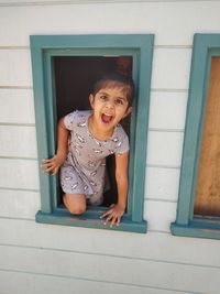 Portrait of smiling woman standing against door