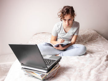 Teenager girl studying online by laptop on the bed 