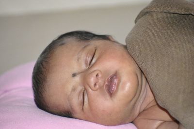 Close-up portrait of cute baby lying on bed