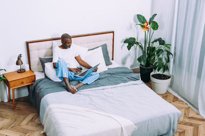 Young woman sitting on bed at home