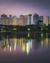 Reflection of illuminated buildings on river in city at night