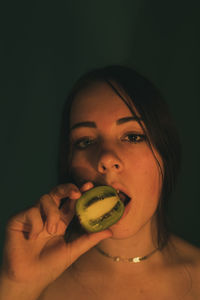 Portrait of young woman holding fruit against white background