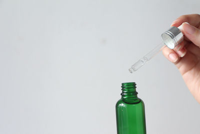 Cropped hand holding syringe against white background