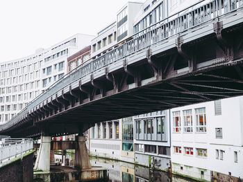 Low angle view of bridge over river against buildings in city