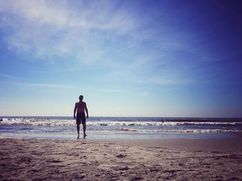 Rear view of man on beach against sky