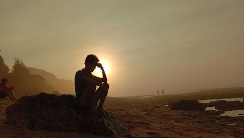 Side view of man on rock during sunset