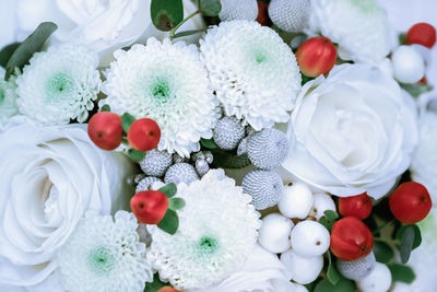 Beautiful white flowers with red berries and green leaves. holiday or wedding decoration background.