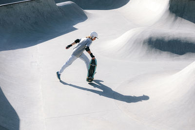 Man wearing helmet running with skateboard on sunny day