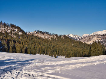 Scenic view of snow covered mountains against clear blue sky