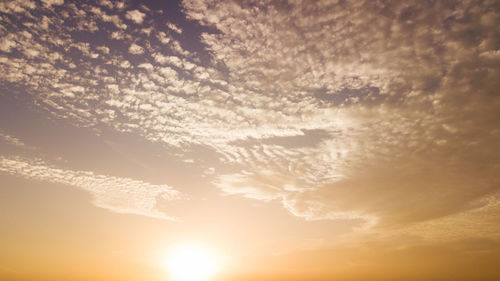 Low angle view of sunlight streaming through clouds