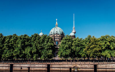 Berlin cathedral by trees against clear blue sky