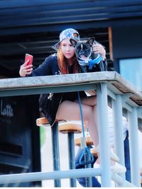 Young woman with dog taking selfie through mobile phone at sidewalk cafe