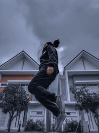 Low angle view of man outside house against sky