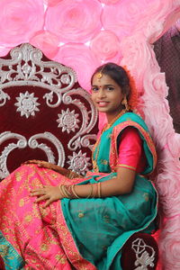 Portrait of smiling woman sitting with pink toys