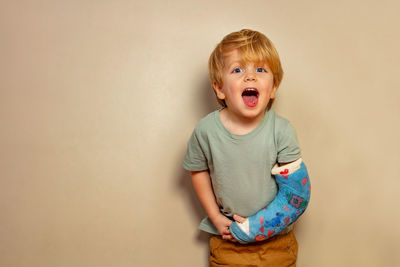 Portrait of cute baby boy standing against wall