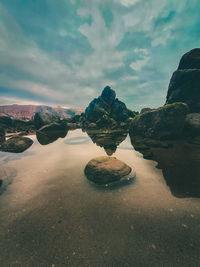 Rock formations on beach against sky