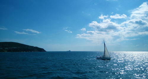 Sailboat sailing on sea against blue sky
