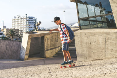 Full length of boy skateboarding in city