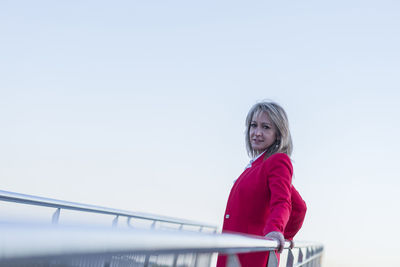 Portrait of young woman standing against clear sky