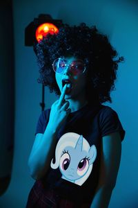 Portrait of young woman holding illuminated lighting equipment