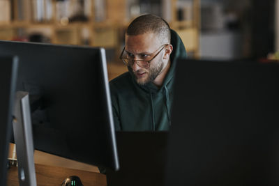 Young male programmer working on computer in startup company