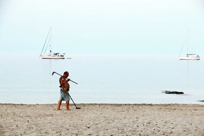 Rear view of man standing on beach against clear sky