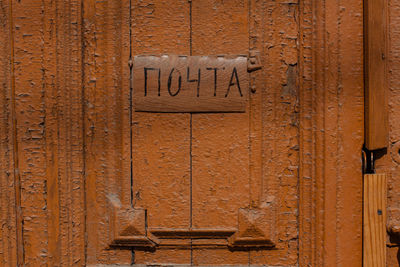 Close-up of nameplate on brown wooden door