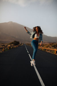 Full length of woman jumping on road during foggy weather