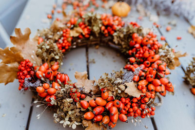 Close up photo of handmade colorful floral autumn door wreath made of colorful rosehip berries