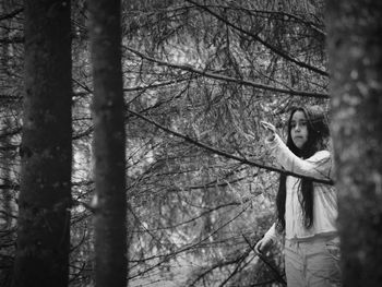 Girl looking away while standing in forest