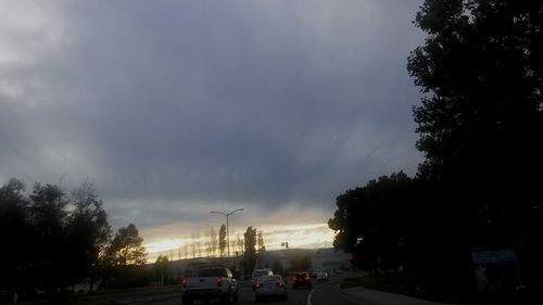 Cars parked on road against cloudy sky