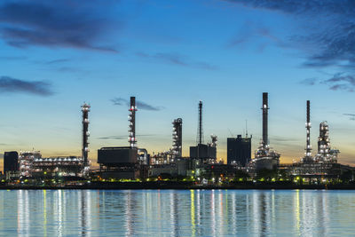 Illuminated factory against blue sky