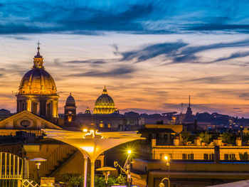 Illuminated buildings in city against sky during sunset