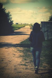 Woman standing on field against cloudy sky