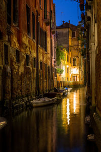 Canal amidst buildings in city at night