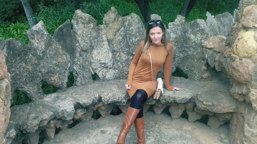 Full length portrait of beautiful woman sitting on stone seat at park guell