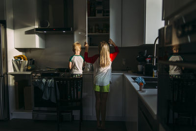 Rear view of siblings standing in kitchen at home