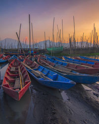 Boats moored in marina at sunset