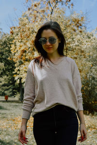 Young woman wearing sunglasses while standing against trees