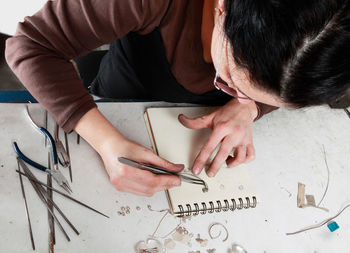 High angle view of woman making jewelry in workshop