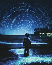 Rear view of woman standing against sky at night