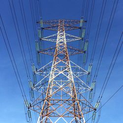 Low angle view of electricity pylon against blue sky
