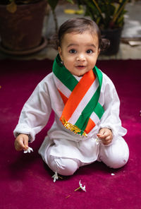 Cute toddler holding indian tricolor flag in traditional cloth with innocent facial expression