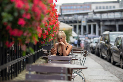Young woman sitting at sidewalk cafe in city