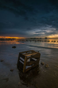 Abandoned boat on beach against sky during sunset