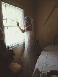 Young woman standing on bed at home