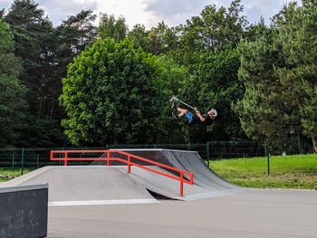 Man jumping by railing against trees